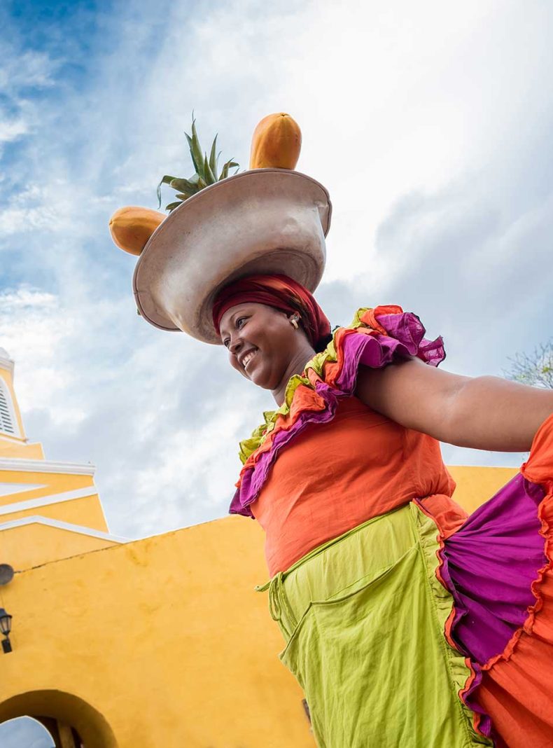 mujer palenquera con cesta de frutas en la cabeza Colombia