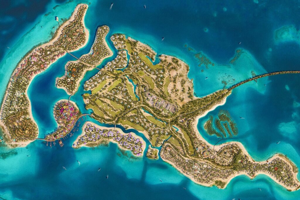 Aerial view of a tropical island resort with villas, bridges, and turquoise lagoons bordered by white-sand beaches.