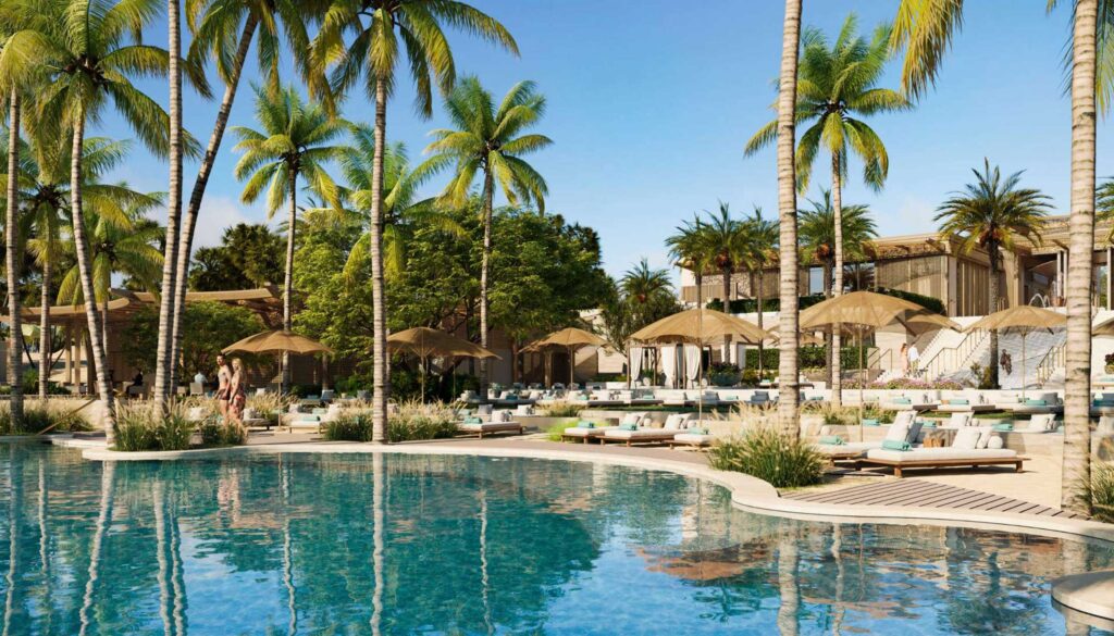 Resort pool area with palm trees, beige umbrellas, and lounge chairs along a sunny deck under a blue sky